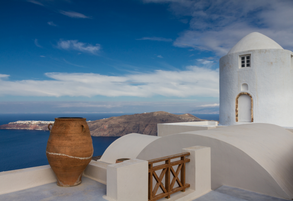 white classic greek architecture overlooking the ocean and an outcrop island.